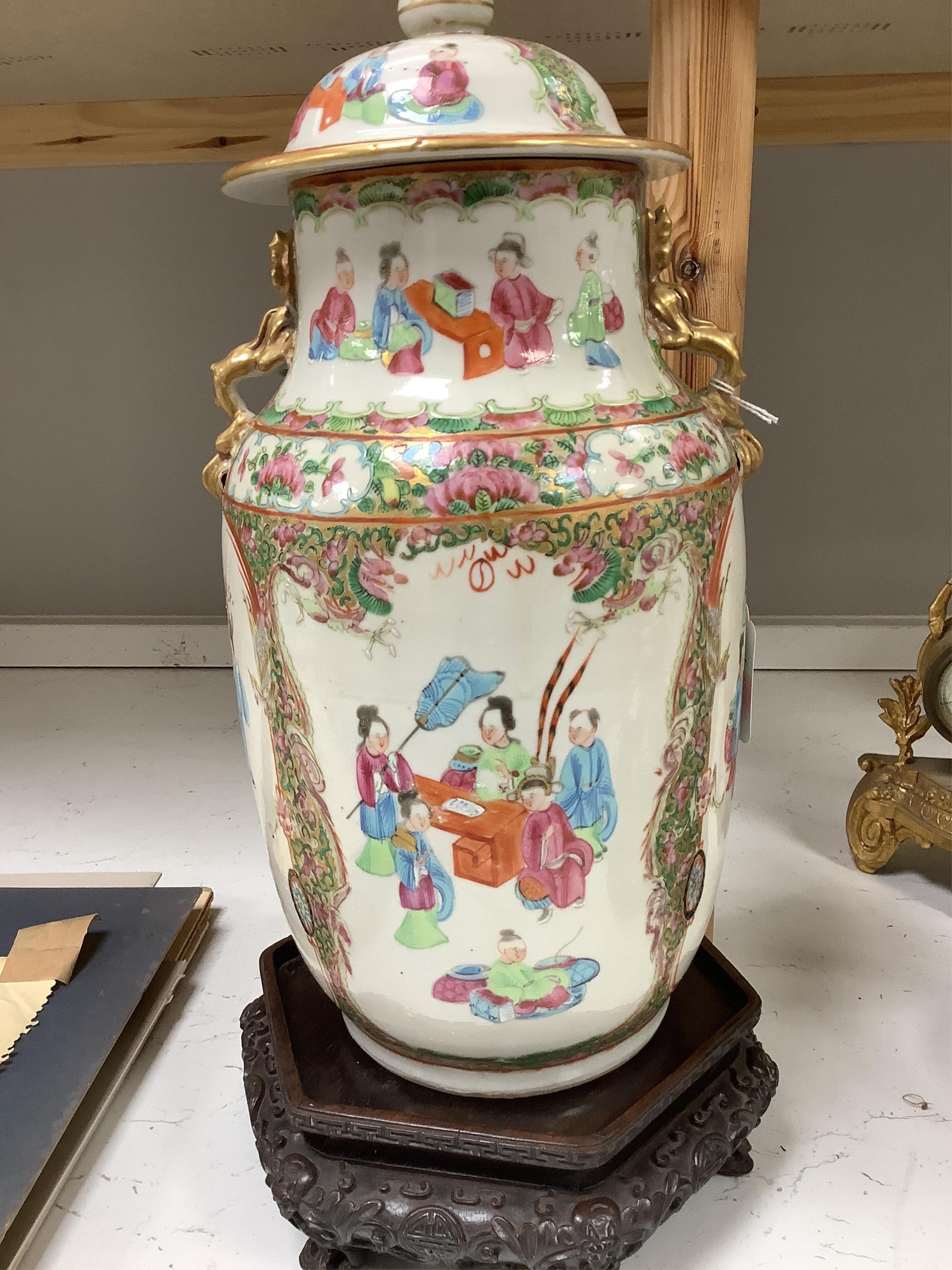 A Chinese famille rose vase and cover, late 19th century, together with a good carved hongmu ‘bats and shou’ stand, vase 36cm. Condition - crack to rim